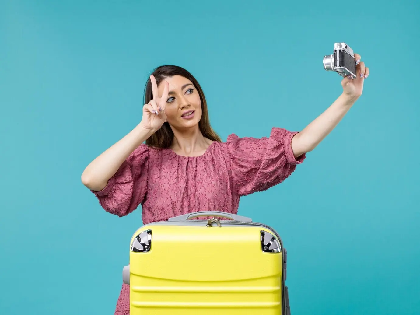 Вид спереди: молодая женщина, отправляющаяся в отпуск и делающая фото на голубом фоне; путешествие за границу, морской отдых.